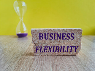 Concept words Business flexibility on brick blocks. Beautiful yellow background, hourglass....