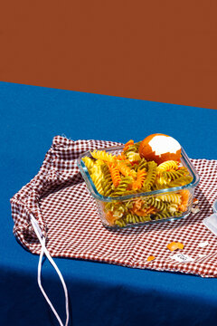 Pasta kept in container with boiled egg over red checked bag