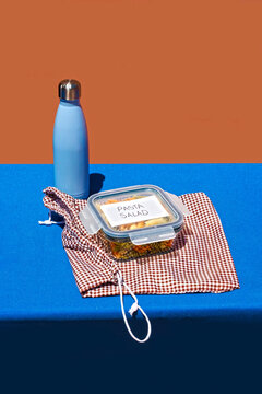 Lunch box with pasta kept near water bottle on blue table