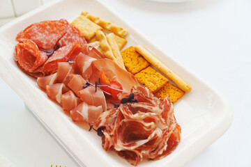 A plate with cold cuts and breadsticks. A delicious jerky appetizer.