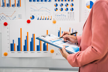 A businesswoman works diligently at her desk, reviewing financial documents and analyzing investment data. She ensures accuracy and efficiency in financial calculations and audit processes.