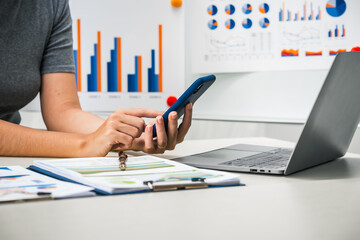 A businesswoman works diligently at her desk, reviewing financial documents and analyzing...