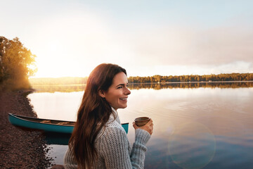 Nature, river and woman with coffee to enjoy, sunrise and outdoor with smile in vacation and morning. Break, relax and girl with joy for inspiration in countryside of Finland with peace by lake
