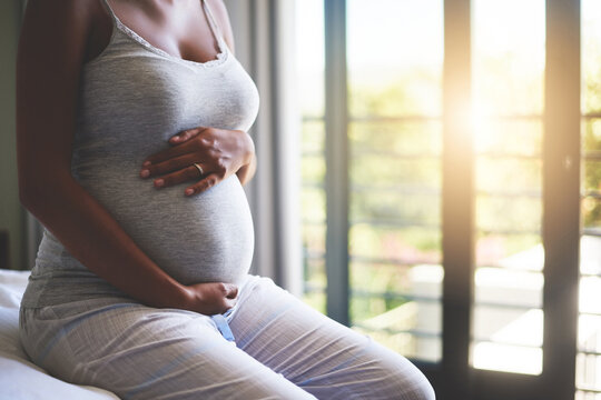 Woman, pregnant and hands on stomach for growth, bonding and maternal health as motherhood on bed. Mother, abdomen and pregnancy with care for feeling movement, connection and relax in home bedroom
