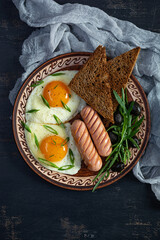 Fried eggs with sausage, arugula, olives and toasts. Delicious breakfast