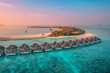 Amazing aerial beach landscape. Beautiful Maldives sunset nature seascape view. Horizon colorful sea sky clouds luxury resort villas. Tranquil drone view island lagoon tourism travel exotic vacation