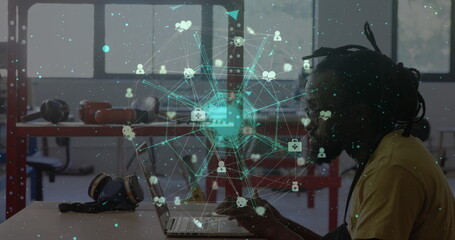 Image of network of connections with icons over african american businessman using laptop