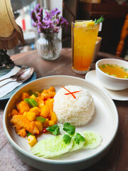 Rice and fried chicken with vegetable tomato sauce on plate.