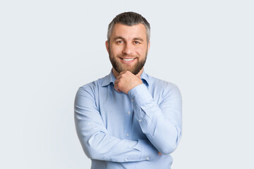 A man in a blue shirt is striking a pose for a photograph. He stands confidently as he smiles at the camera, displaying a relaxed and casual demeanor.
