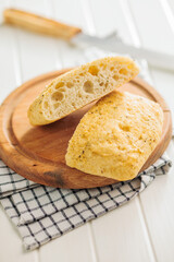 Italian ciabatta bread on cutting board on white table.