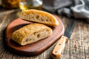 Italian ciabatta bread on cutting board on wooden table.