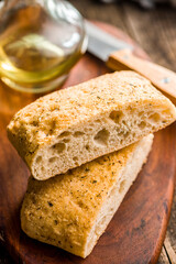 Italian ciabatta bread on cutting board on wooden table.