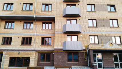 Fototapeta premium Facade of new multi-story building. Sale, rental apartments. Housing development. Cityscape. City life. Real estate. Mortgage concept. Condos. Interest Rate Increase. Flat. Brick wall. Built-To-Rent.