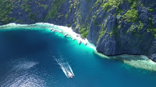 Aerial footage of a boat sailing off Talisay Beach in Tapiutan Island, El Nido, Palawan, Philippines