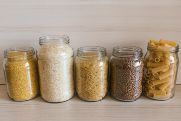 A row of glass jars filled with various types of food.  