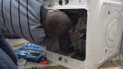master repairs the washing machine, professional repair of household appliances, washing machine repair specialist