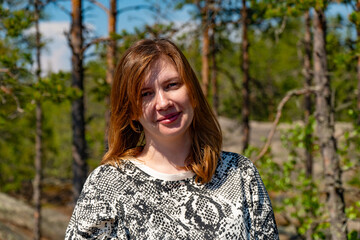 Close-up of a woman relaxing and smiling in a sunlit forest, showcasing her joy and serenity amidst nature. Ideal for themes of relaxation, nature, and outdoor lifestyle.