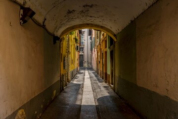 Fototapeta premium Old alley with yellow walls of tenement houses, old town of Italy