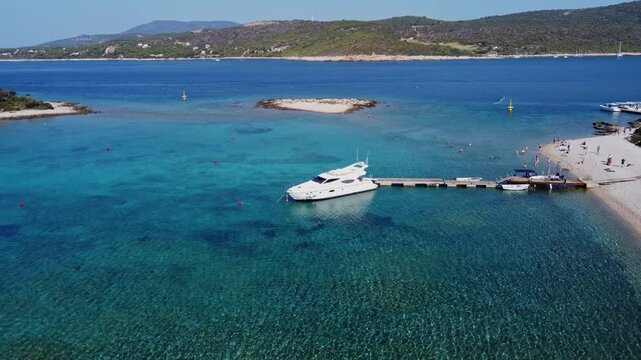 Sunny Croatian Beach With Tour Speed Boat Moored to Boardwalk in Blue Lagoon, Static Drone Shot