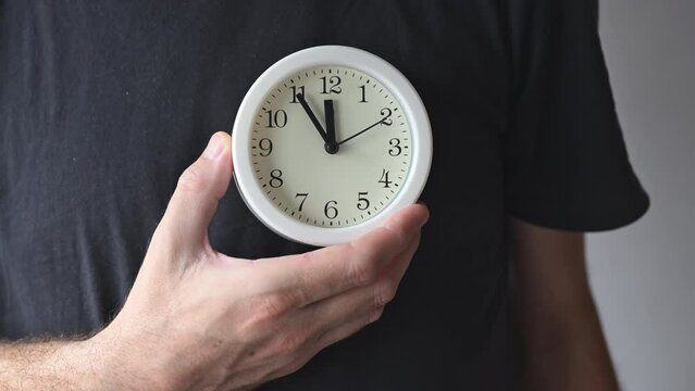 Health clock, adult man holding white alarm clock over his chest