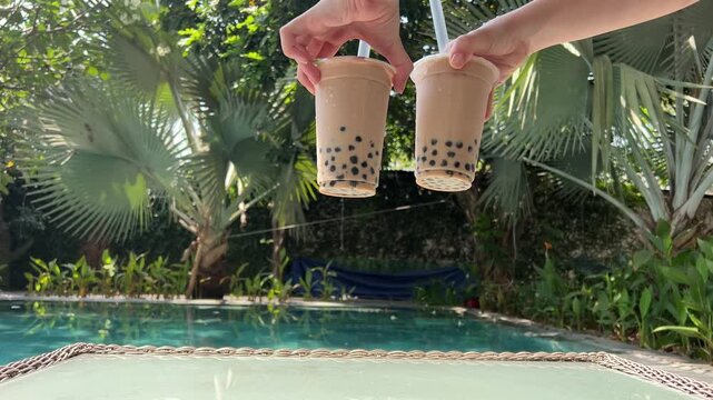 Milk bubble tea with tapioca pearls in glass, gray background. Two Bubble Tea drinks with ice and Tapioca topical balls, a large straw, stir and pierce