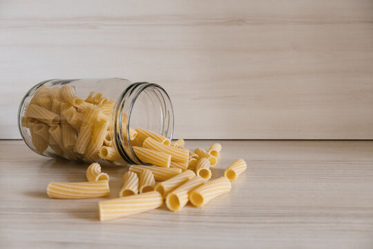 Close up of pasta in a glass jar on a white wooden table