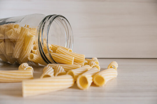 Close up of pasta in a glass jar on a white wooden table