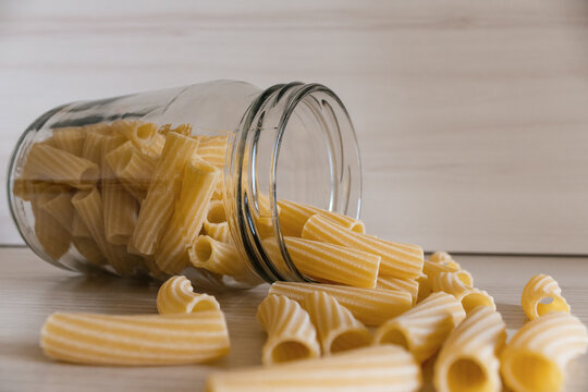 Close up of pasta in a glass jar on a white wooden table