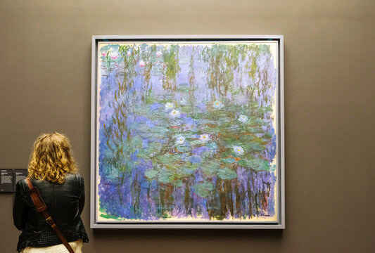 Paris, France - May 4, 2019: Tourists near Blue Water-Lilies or Nymph&eacute;as bleus, an oil painting by french impressionist Claude Monet exposed at the Orsay Museum.