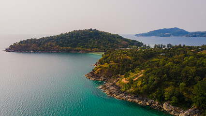 Fototapeta premium Paradise beach Phuket Patong. aerial top view amazing freedom beach small white sand beach with perfect nature. white wave hit the rock around island. green forest peaceful. green sea, landscape.