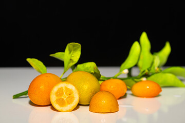 Kumquat fruits with green leaves on a white background. Black background.