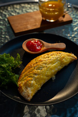 prata curry puff on black plate served alongside with pineapple juice, cafe environment