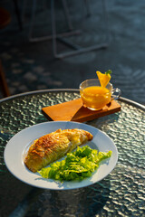 prata curry puff on white plate served alongside with pineapple juice, cafe environment
