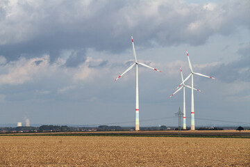 Wind turbines in an open field with cloudy sky in the background