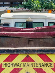 Work in Progress. Highway Maintenance, black letters on red and yellow truck trailer. 