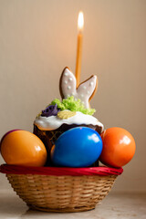 Easter cake with a lit candle. Easter colorful eggs in a basket on the table