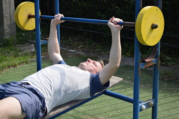 A dedicated young athlete puts in the hard work, vigorously training on gym equipment outdoors to...