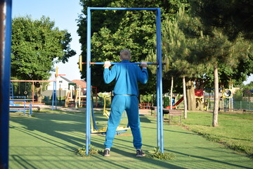 A dedicated young athlete puts in the hard work, vigorously training on gym equipment outdoors to...