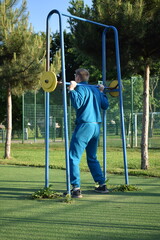 A dedicated young athlete puts in the hard work, vigorously training on gym equipment outdoors to...