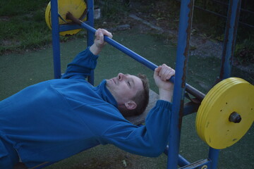 A dedicated young athlete puts in the hard work, vigorously training on gym equipment outdoors to...