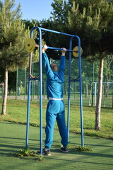 A dedicated young athlete puts in the hard work, vigorously training on gym equipment outdoors to...