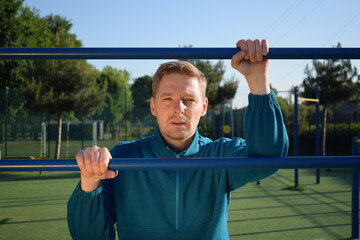 A dedicated young athlete puts in the hard work, vigorously training on gym equipment outdoors to...