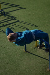 A dedicated young athlete puts in the hard work, vigorously training on gym equipment outdoors to...