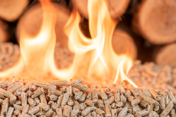 A pile of wood pellets on fire. Behind in defocus there is a wall of wood.