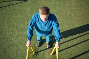 A dedicated young athlete puts in the hard work, vigorously training on gym equipment outdoors to...