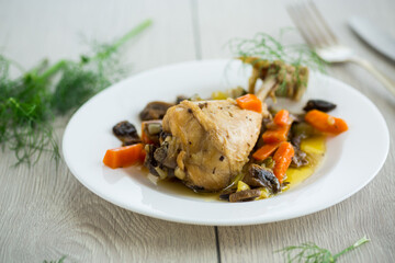 roast chicken with mushrooms and vegetables in a plate on a wooden table