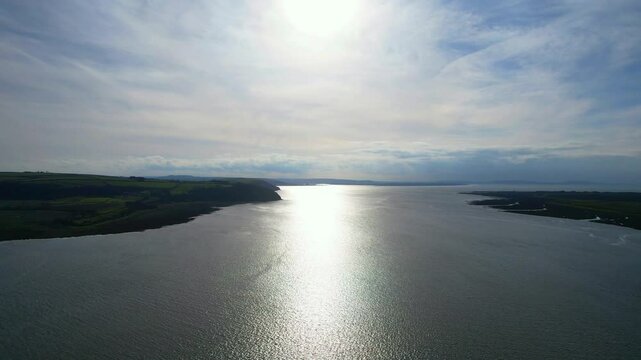 Morning sun reflections on River Coran near Carmarthen Bay in Carmarthenshire, Wales. Drone shot