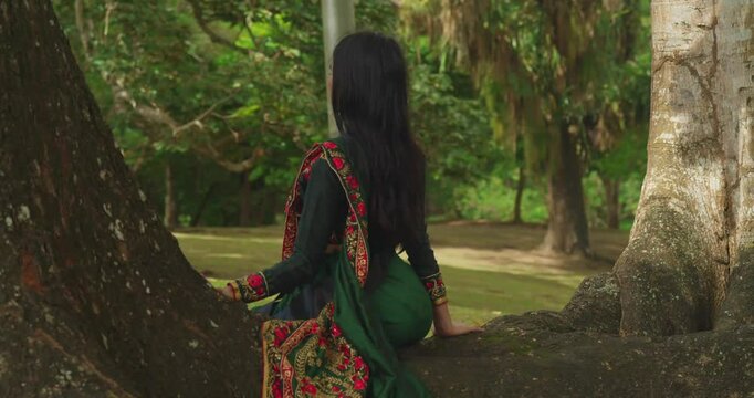 In the Caribbean, a young girl wearing traditional Indian clothes enjoys a day at a tropical park.