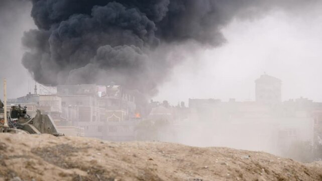 Israeli IDF army tanks carry out military operations in the city of Rafah against a backdrop of dense explosion smoke