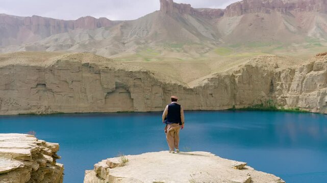 Revealed Afghan Man Over Cliffs Of Band-e Amir National Park In Bamyan, Afghanistan. Aerial Tilt-up Shot